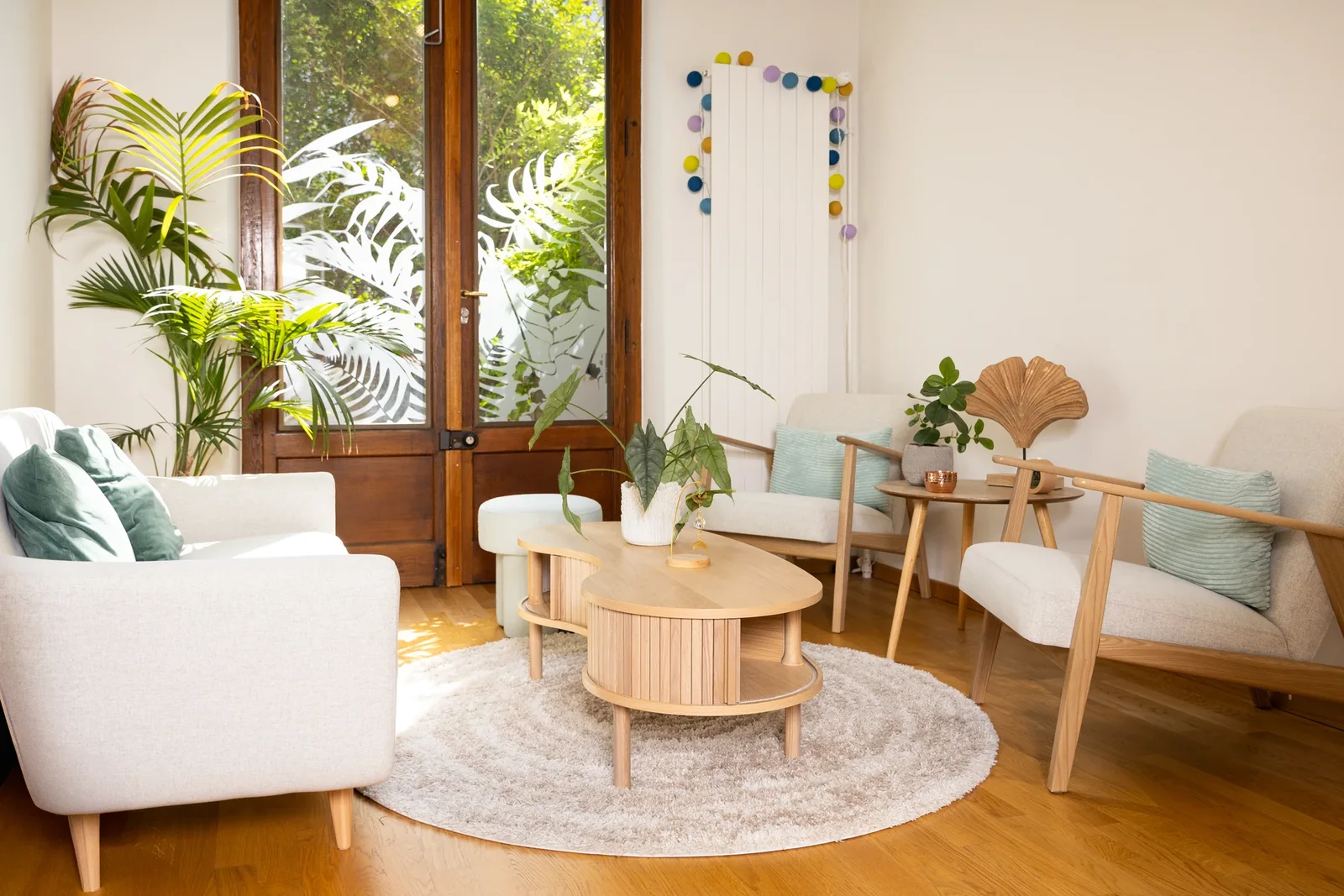 Salon du cabinet ouvert sur la baie vitrée, fauteuils clairs et végétal